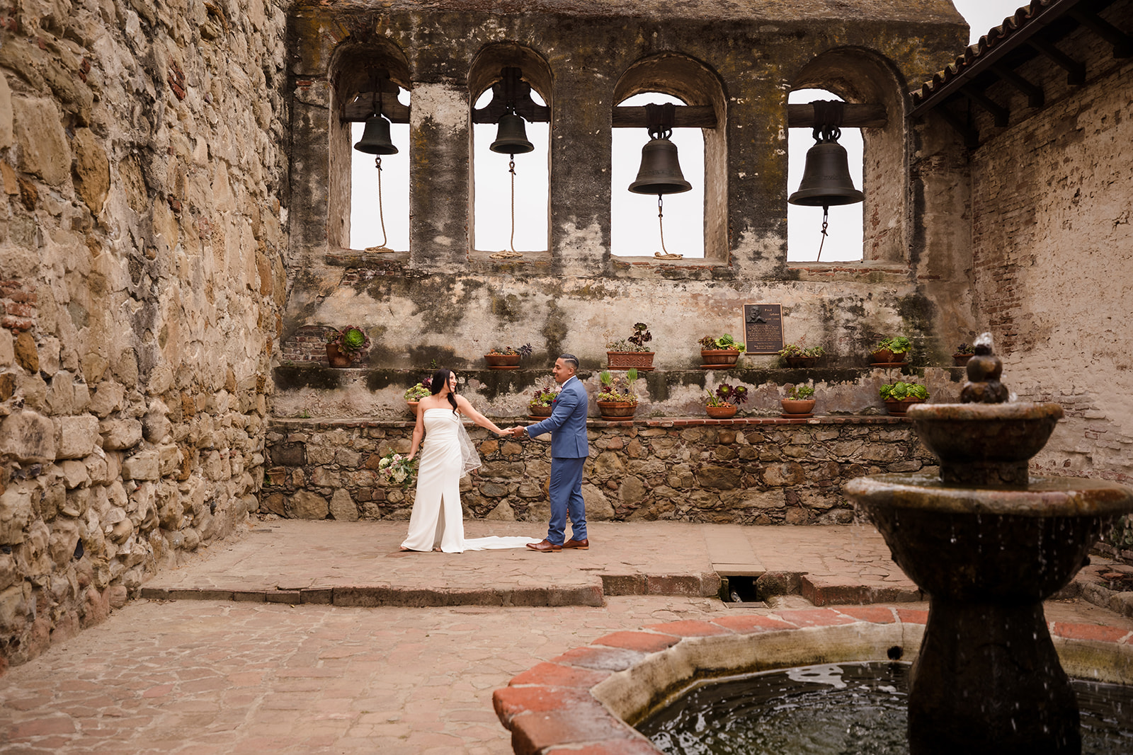 Bride and groom walk in the Sacred Garden at Mission San Juan Capistrano