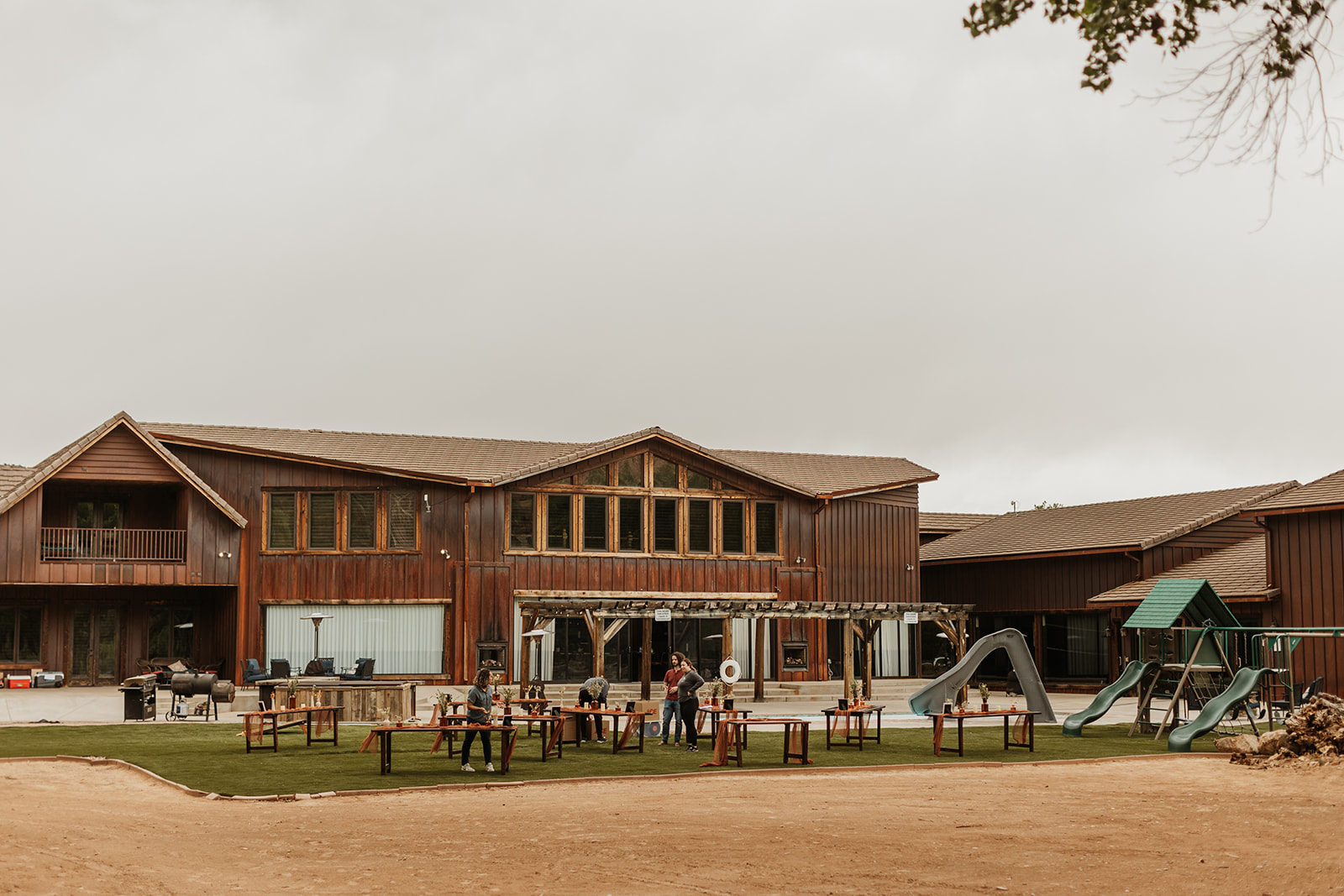 A wide view of the exterior of Zion Red Rock Oasis with an overcast sky and tables being set up 