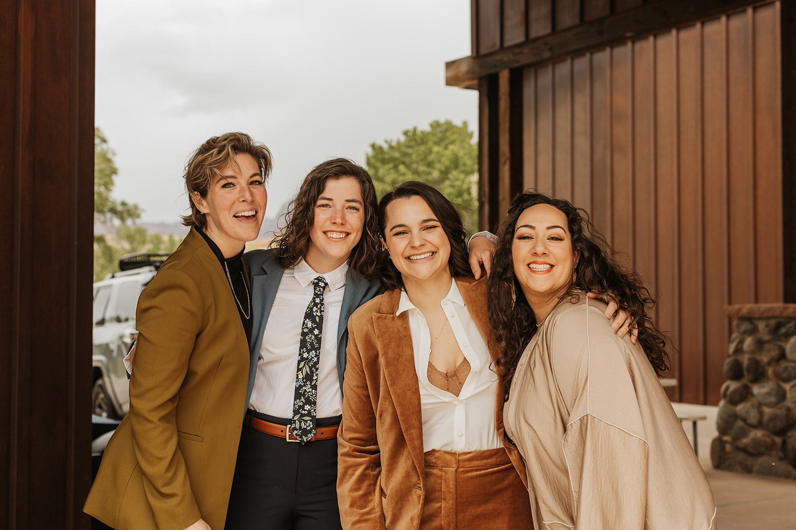 Four women gathered for a group photo in front of a wooden building 