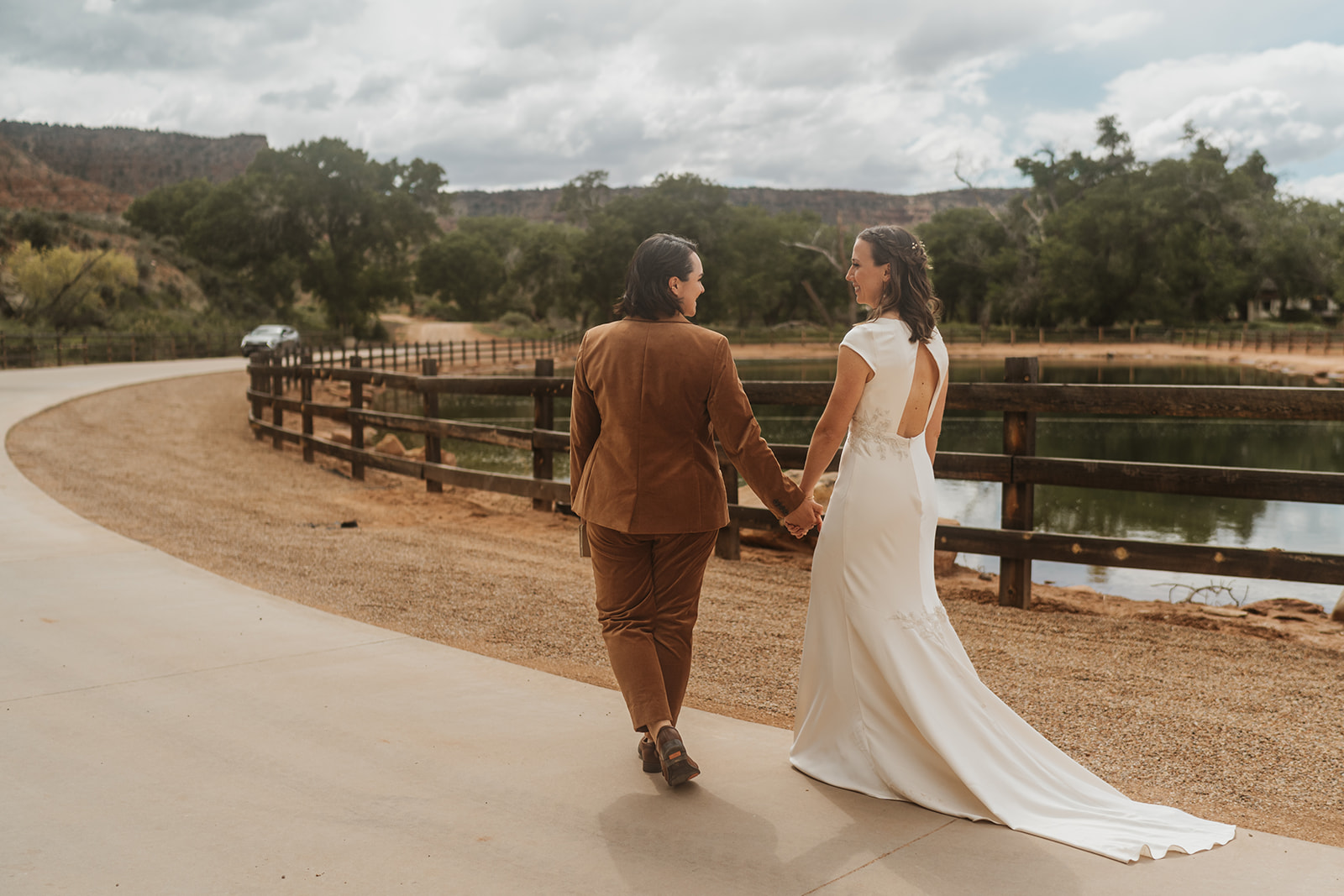 Two brides walking to their ceremony holding hands 