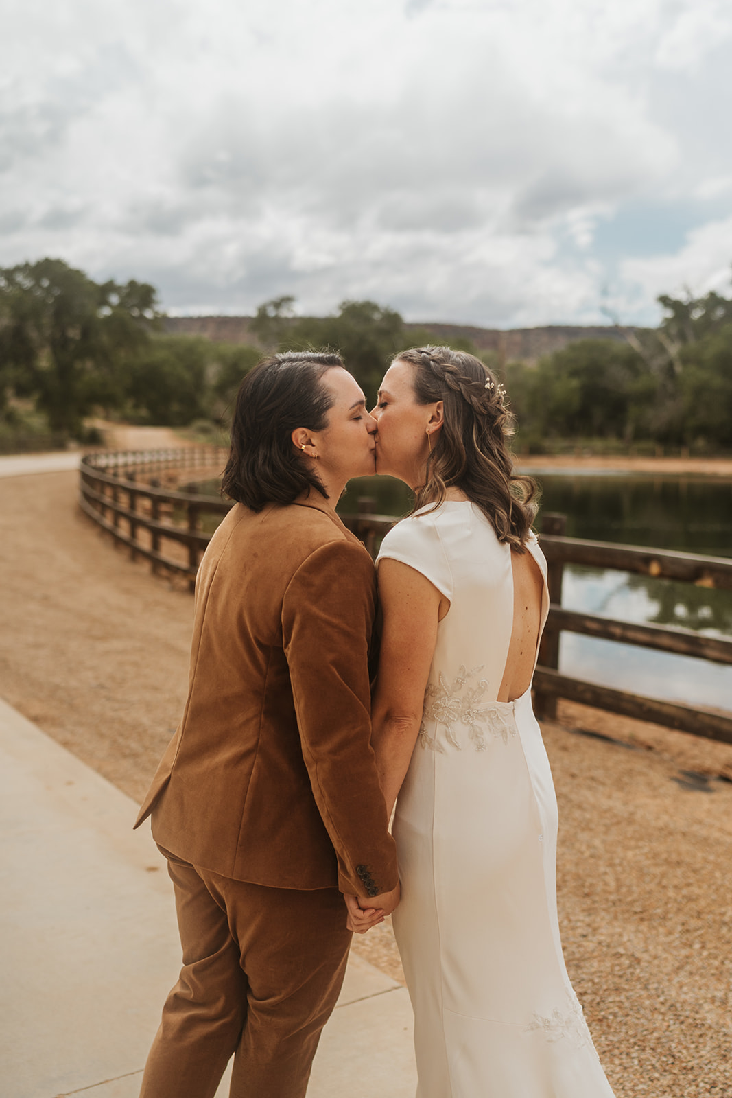 Two brides walk away kissing before heading to their ceremony 