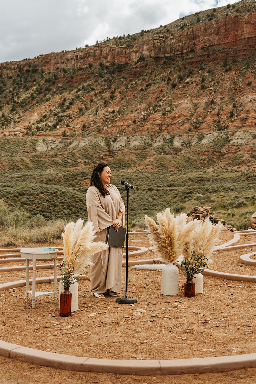 A woman standing at the center of a wedding ceremony with mountains behind her 