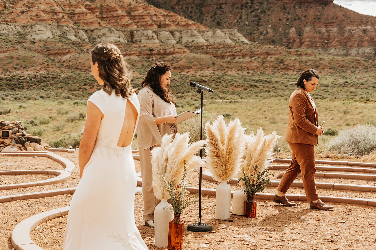 Two brides walking through the ceremony labyrinth with their officiant in the middle  