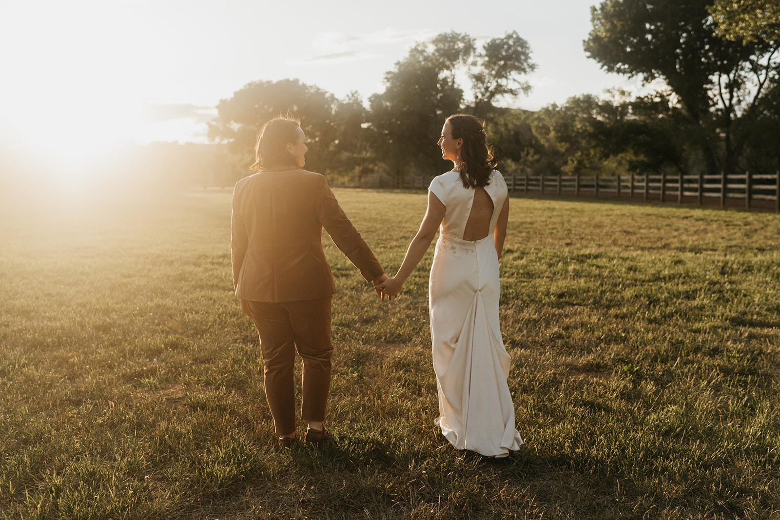 Two brides embracing on their wedding day at sunset 