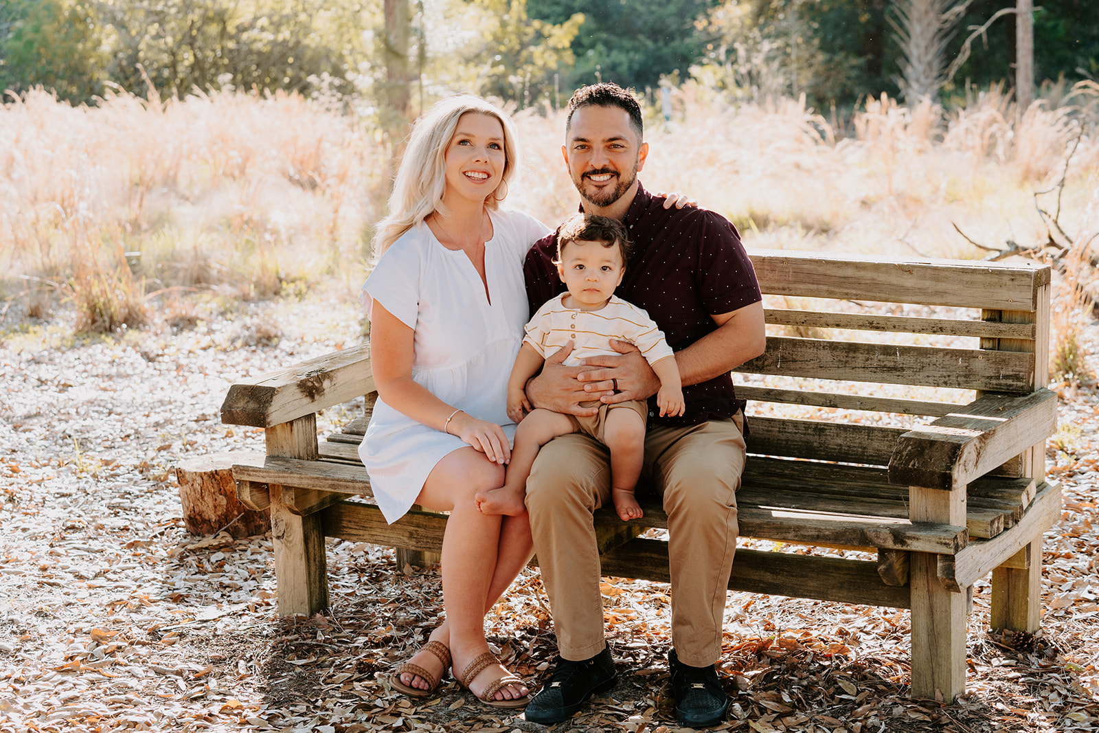 Family of three posing happily together on a bench at Oakland Nature Preserve