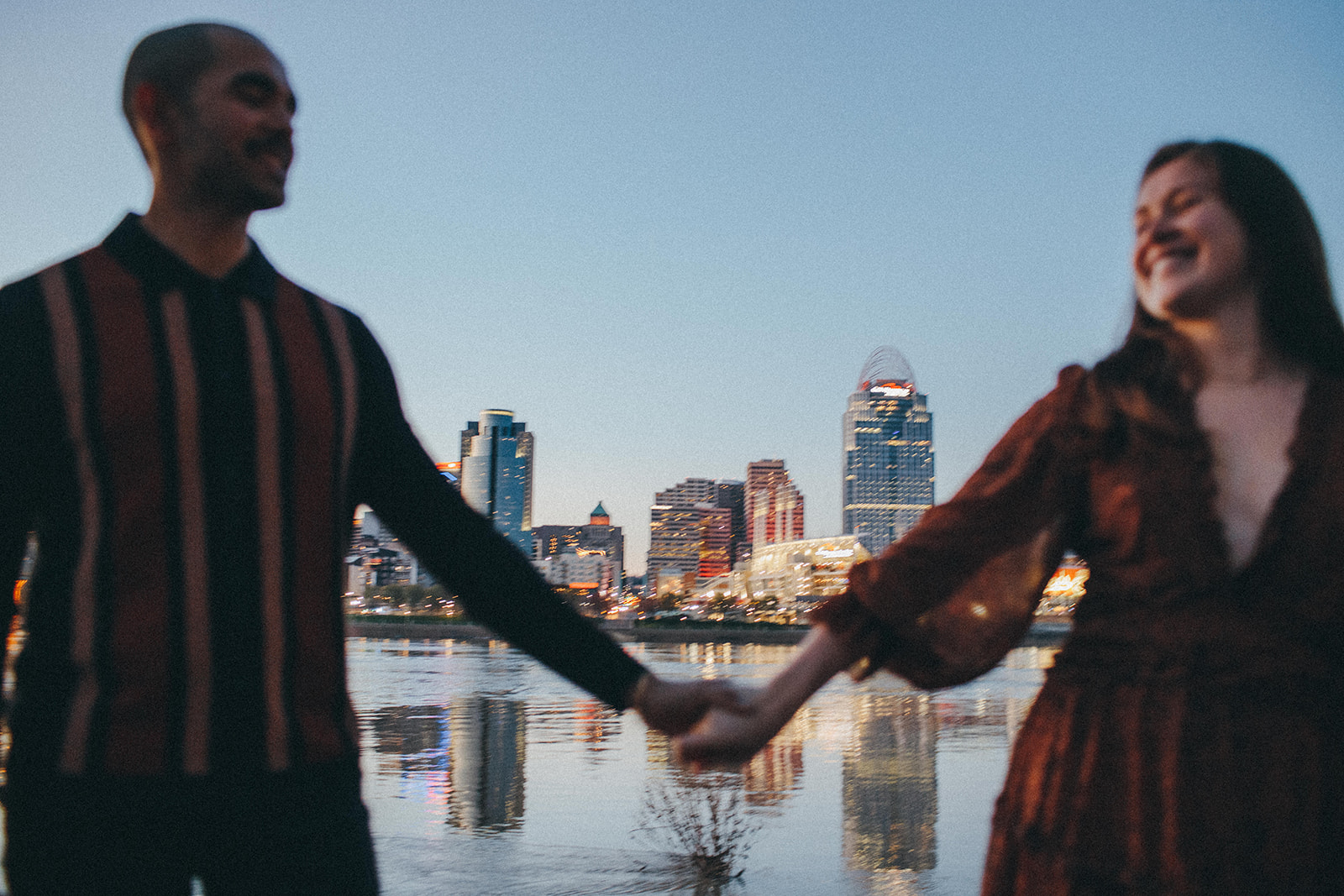 A documentary candid moment between a couple as they walk away from the Ohio River and downtown Cincinnati