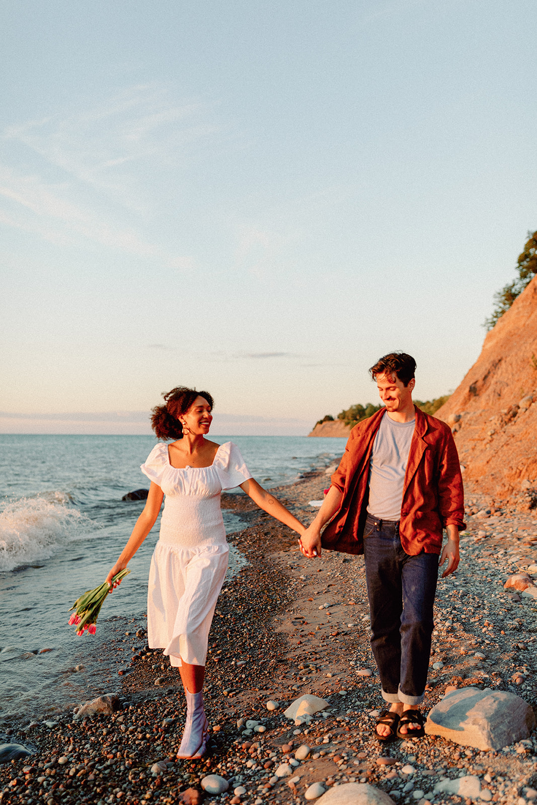A couple holding hands during their Rochester NY engagement session at Chimney Bluffs