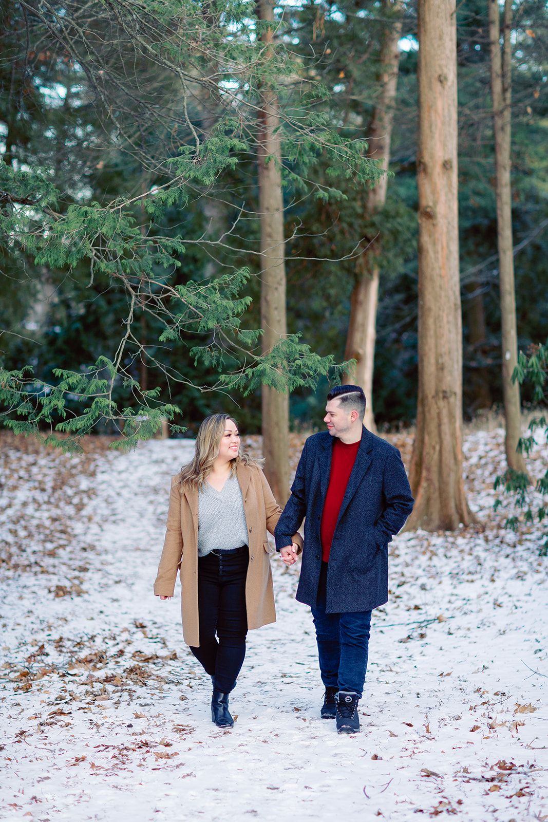 A couple holding hands while walking in Highland Park during their Rochester NY engagement session. 
