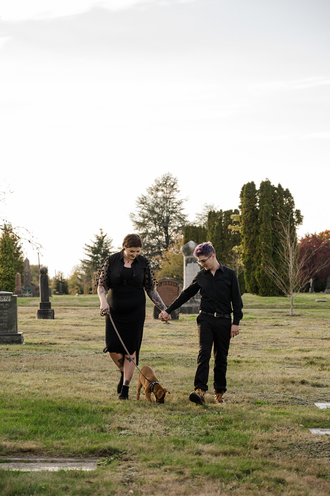 couple walking with puppy in cemetery during their engagement session