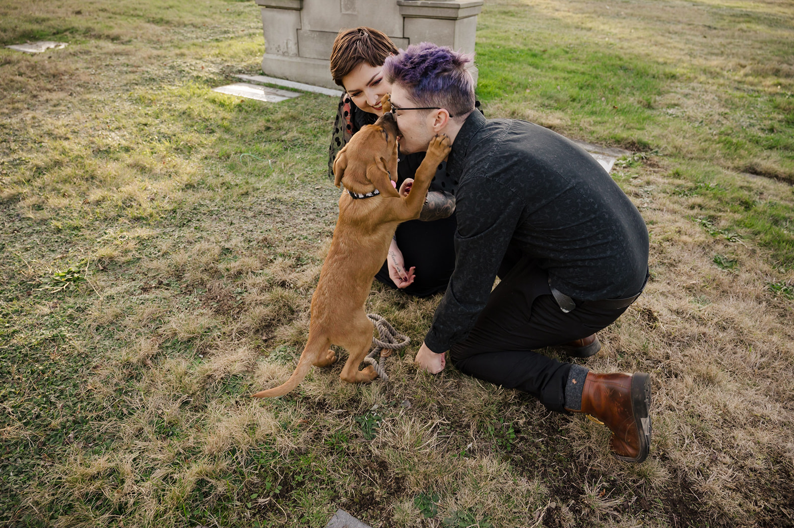 engagement photo of couple playing with puppy in cemetery