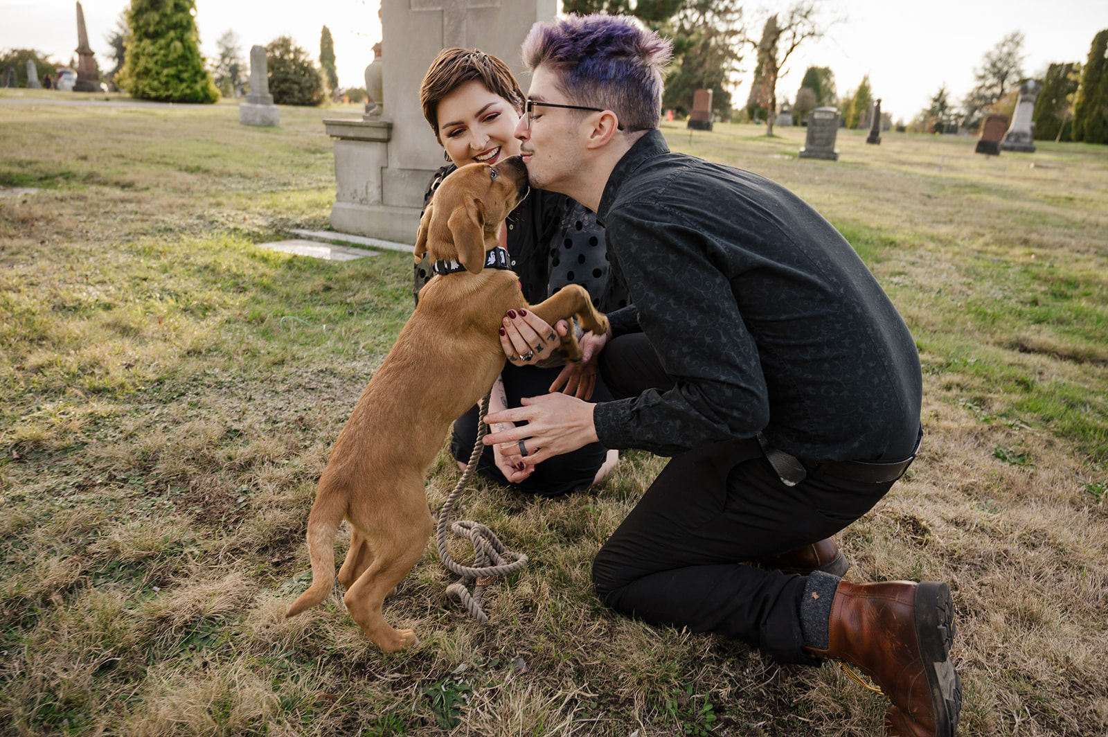 engagement photo of couple playing with puppy in a cemetery