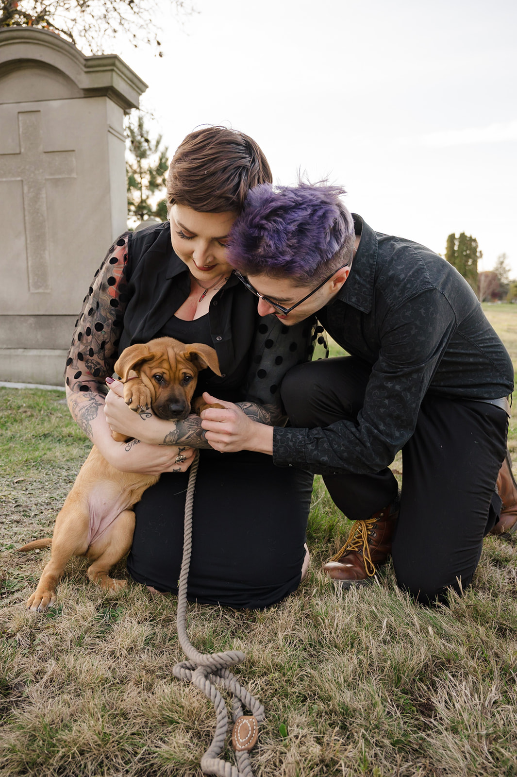 engagement photo of couple playing with puppy in a cemetery