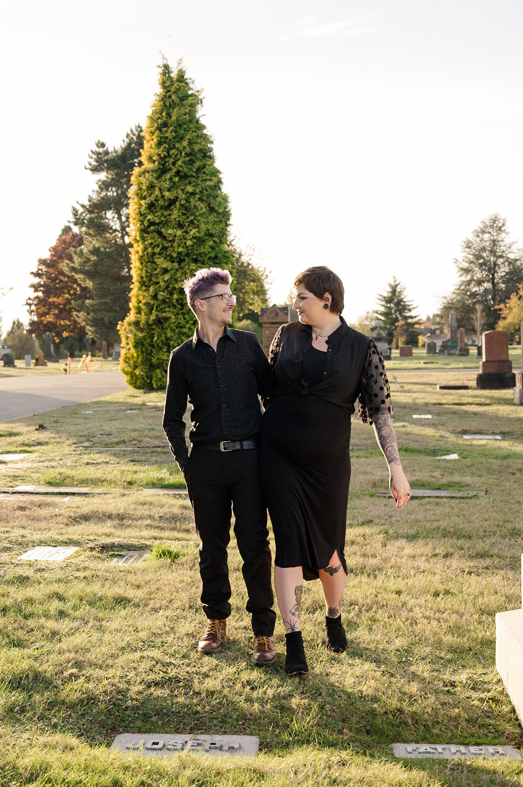 engagement photo of couple walking at sunset in a cemetery